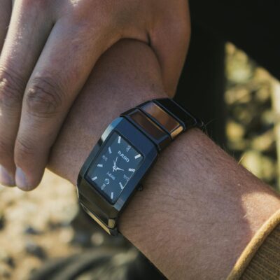 A fashionable black wristwatch elegantly worn on a man's wrist, showcasing modern style.