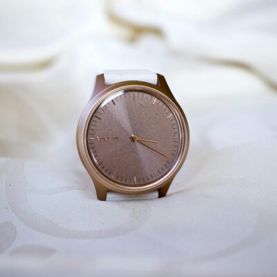 Close-up of a rose gold watch on a white fabric, showcasing minimalistic elegance and style.