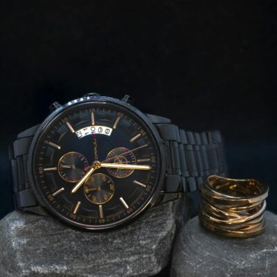 Photo by Jordan Rushton Stylish black wristwatch on stone with a copper ring, perfect for sophisticated fashion.